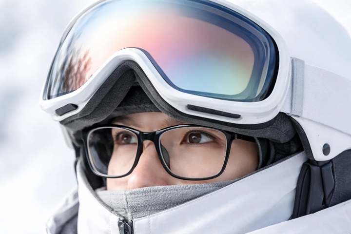 Крупний план: гірськолижна маска злегка піднята, видно окуляри під нею (OTG), м’яке зимове світло, мінімальний фон